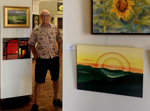 Frank Oliva standing next two his Aboriginal style art at Arts at Marks Garage in august 2024