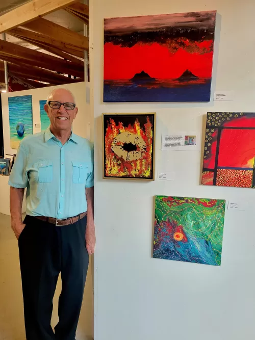 Frank Oliva standing next two his Aboriginal style art at Arts at Marks Garage in august 2023